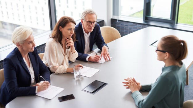Woman during job interview and three elegant members of management