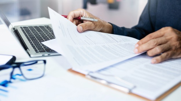 Businessman reviewing document reports at office workplace with computer laptop. legal expert, professional lawyer reading and checking financial documents or insurance contract