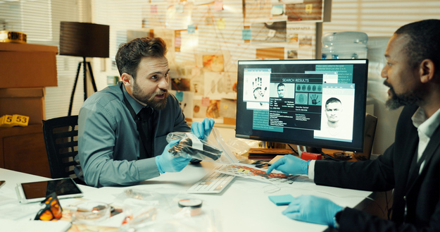 Computer screen, collaboration and plastic bag with detective people in office at night. Conversation, evidence and investigation with police team at desk in workplace for evening review of clues